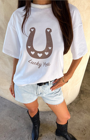 Close up of girl wearing a white western tee, black belt, denim shorts and black boots.