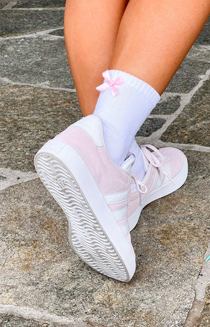 White crew socks with small pink bow on model wearing pink adidas shoes.